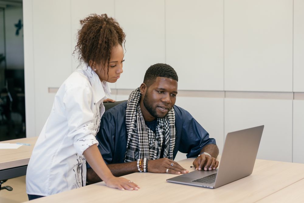 Two colleagues reviewing information on a laptop