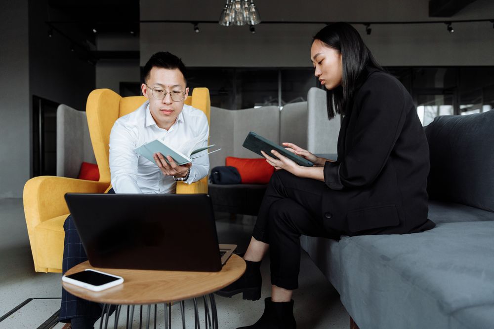 Two professionals discussing work beside a laptop